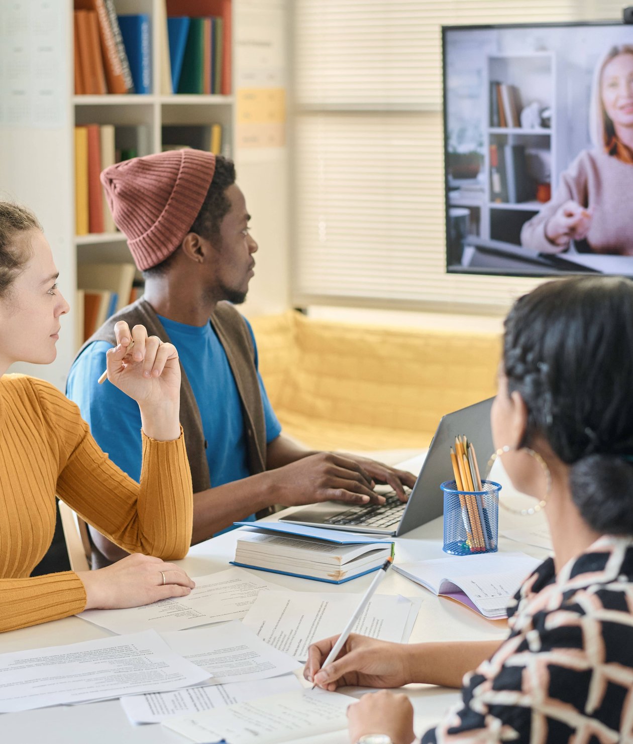 Students attending remote class with instructor displayed on large screen